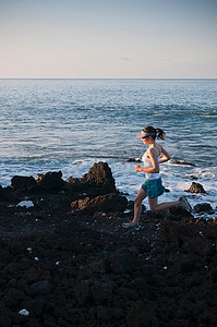 海滩奔跑的美摄影照片_一名女子在岩石海滩上奔跑