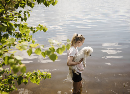 芬兰奥里维西一名妇女站在湖中抱着一只名叫乌里尔的狗