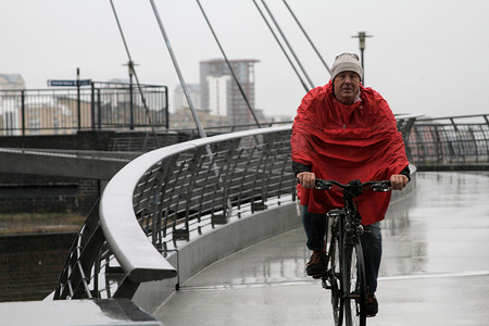 下着雨摄影照片_穿雨衣骑自行车的男人