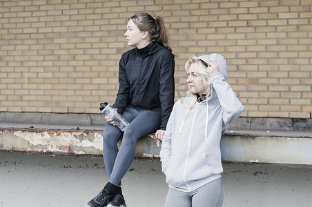 两名女性跑步朋友在仓库外侧视