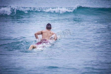 年轻的男性冲浪者躺在海上的冲浪板上卡利亚里撒丁岛意大利