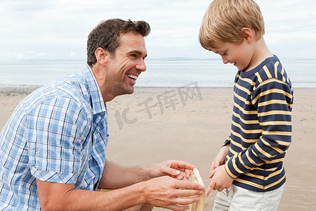定位孩子摄影照片_海滩上的父子带着板球树桩