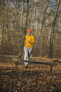一名年轻女子在森林中的突击赛道上向栅栏跑去