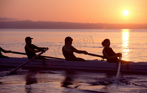 团队划船摄影照片_四个人在日落时划船