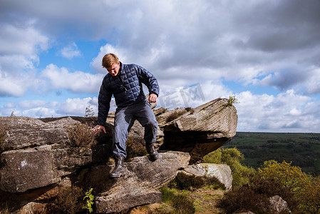 一名十几岁的男性徒步旅行者在约克郡山谷尼德代尔的帕特利桥吉斯悬崖上走下岩石