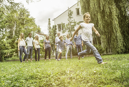 准备跑步的人摄影照片_在花园里跑步的女孩背景是家人