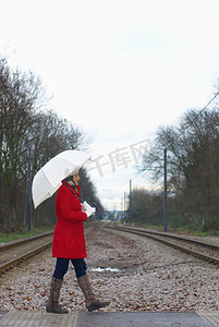 公园里穿红色夹克带雨伞的女孩