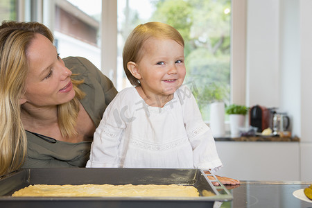 厨房里蹒跚学步的女孩和母亲的肖像