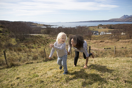 苏格兰赫布里底斯斯凯岛的母亲在田野里追赶儿子