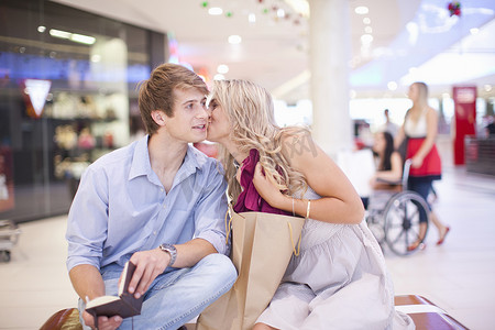 一名年轻女子在商场亲吻男子的脸颊