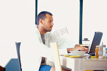 一名男子在早餐桌上使用笔记本电脑