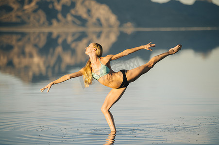 美国犹他州波纳维尔盐滩湖上一条腿站立的女芭蕾舞演员
