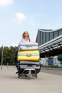 行李车摄影照片_一名中年妇女推着行李车去机场