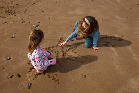 两名儿童在海滩上画星星