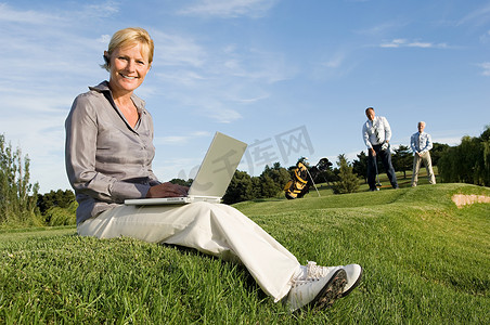 一名女商人在高尔夫球场上使用笔记本电脑