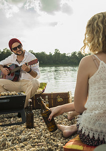 坐在湖边弹吉他的年轻人
