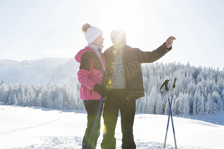 智能造摄影照片_一对老年夫妇在雪地上用智能手机拍照奥地利蒂罗尔的