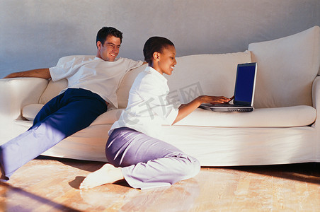 一对夫妇在沙发上一起使用笔记本电脑