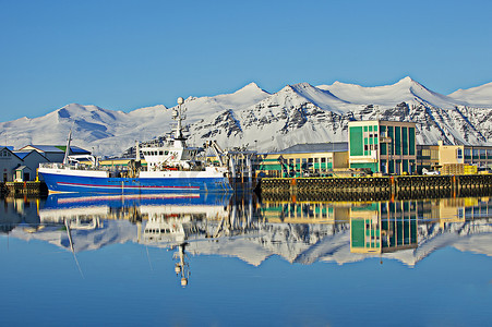 冰岛霍芬港口渔船和白雪覆盖的山脉的景色