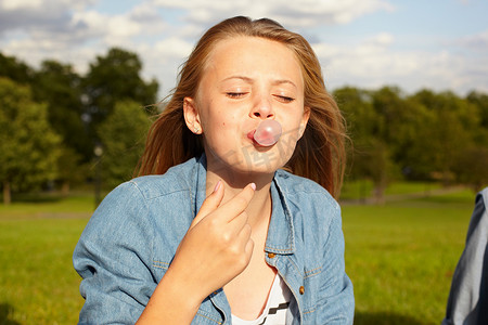 十几岁的女孩在公园里吹泡泡糖