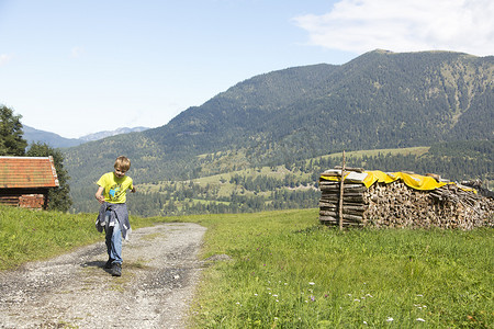 德国巴伐利亚州埃克鲍尔·贝·加米施一个男孩在山上的土路上奔跑
