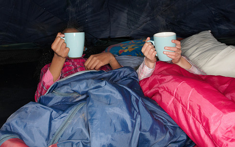黑帐篷摄影照片_女孩们在帐篷里喝着热饮