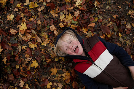 躺在秋叶上的小男孩