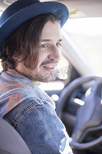 一位戴着帽子坐在车里微笑的年轻人