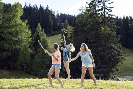 三个成年女性朋友在田野里吹泡泡跳着玩泡泡奥地利蒂罗尔的