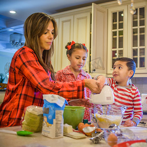 摄影照片_母亲和孩子在厨房里使用手动搅拌器