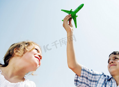 男孩和女孩抬头看着玩具飞机