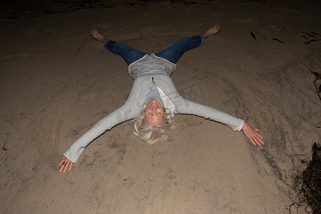 成熟的女人四肢张开躺在沙滩上