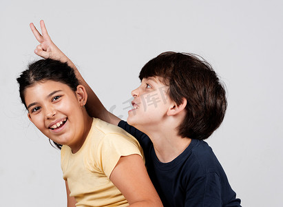 小男孩和小女孩玩耍小男孩举起手指当兔子耳朵