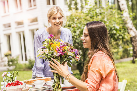 两个女性朋友在花园里看着一束花