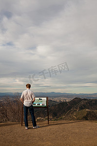 城市复牌摄影照片_美国加利福尼亚州一名男子正在阅读信息牌