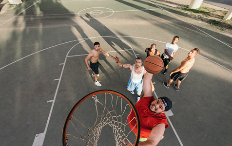 篮球场上做扣篮的年轻人的高角视角