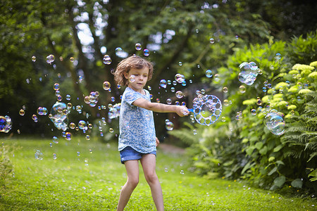 女孩挥舞着泡泡魔杖在花园里吹泡泡