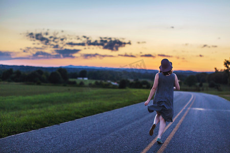 日落时分一名女子在乡间小路上奔跑