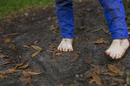 站在花园土壤里的四岁女孩泥泞的脚