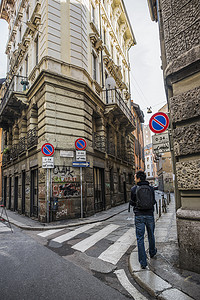 太空涂鸦摄影照片_意大利米兰一名年轻人走在满是涂鸦的街道上