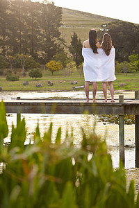 两名年轻女子裹着毯子站在河堤上