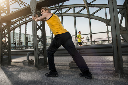 一摊摄影照片_德国巴伐利亚州慕尼黑一名男子在桥上伸展身体