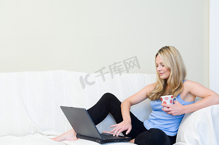坐在沙发上拿着笔记本电脑的女人