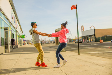 美国布鲁克林十几岁的男孩和女孩在人行道上相互旋转