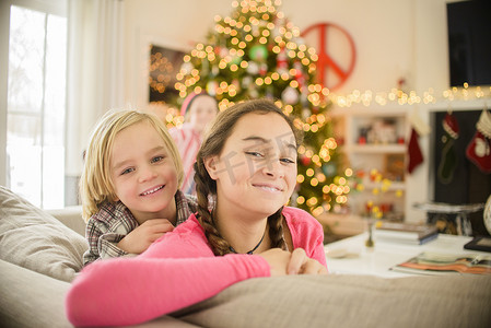 十几岁的女孩和哥哥在圣诞节靠在沙发上的肖像