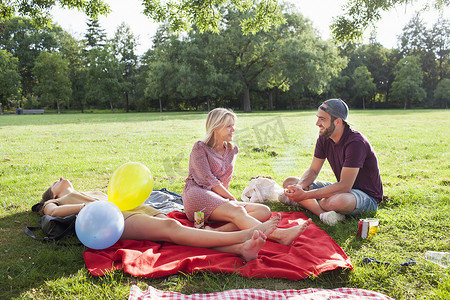 一对年轻男女在公园聚会上用野餐毯子聊天