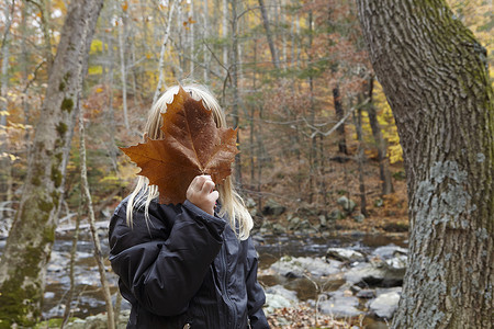 森林里用枫叶遮脸的女孩