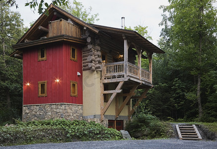 小屋风格的原木房屋的背景在夏天的黄昏石头米色灰泥和红色垂直木壁板外部饰面和木材木质阳台
