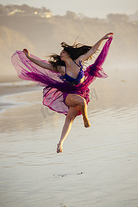 美国加利福尼亚州圣地亚哥穿着雪纺连衣裙的年轻女舞者在海滩上跳舞
