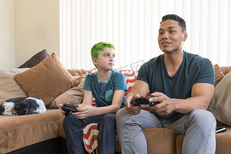 父子俩在沙发上玩电子游戏